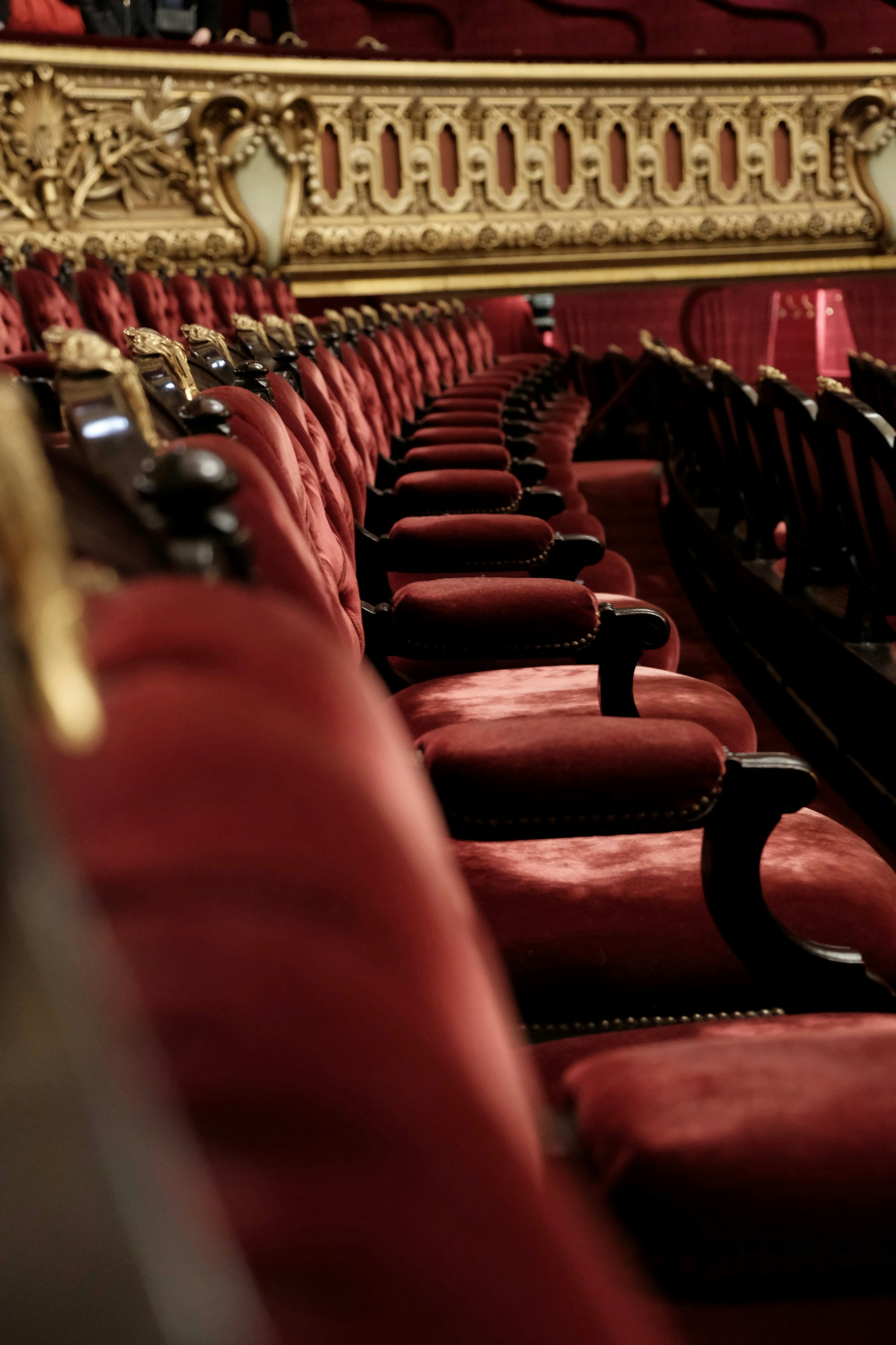 Rows of red velvet seats beneath a gilded opera balcony